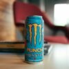 Close-up of Monster Punch energy drink can on a table in a cozy indoor setting.