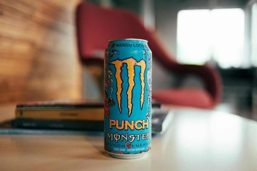 Close-up of Monster Punch energy drink can on a table in a cozy indoor setting.